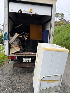 福岡市博多区の一戸建てで、不用品をアルミ箱車に積み込んでいる途中の様子。手前に冷蔵庫、荷台にテレビや家具類