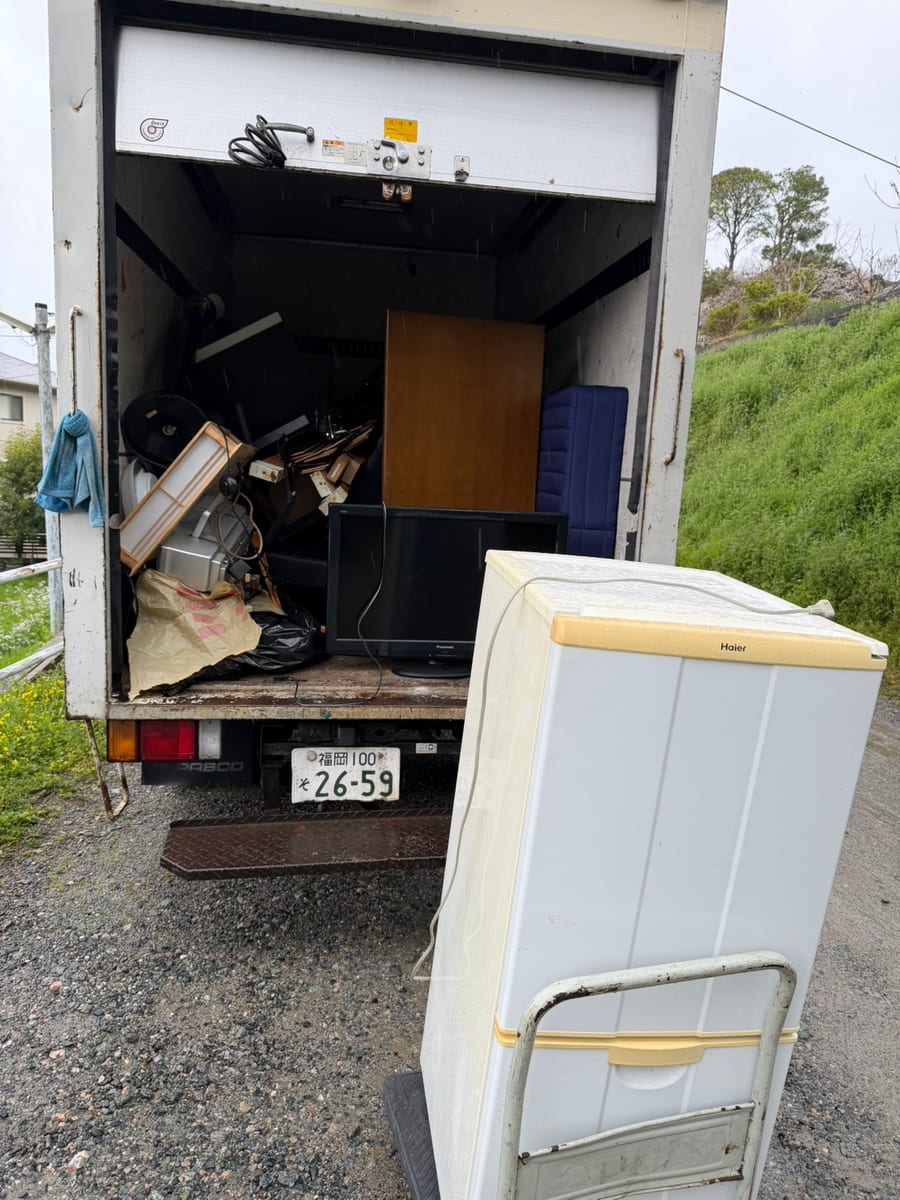 福岡市博多区の一戸建てで、不用品をアルミ箱車に積み込んでいる途中の様子。手前に冷蔵庫、荷台にテレビや家具類