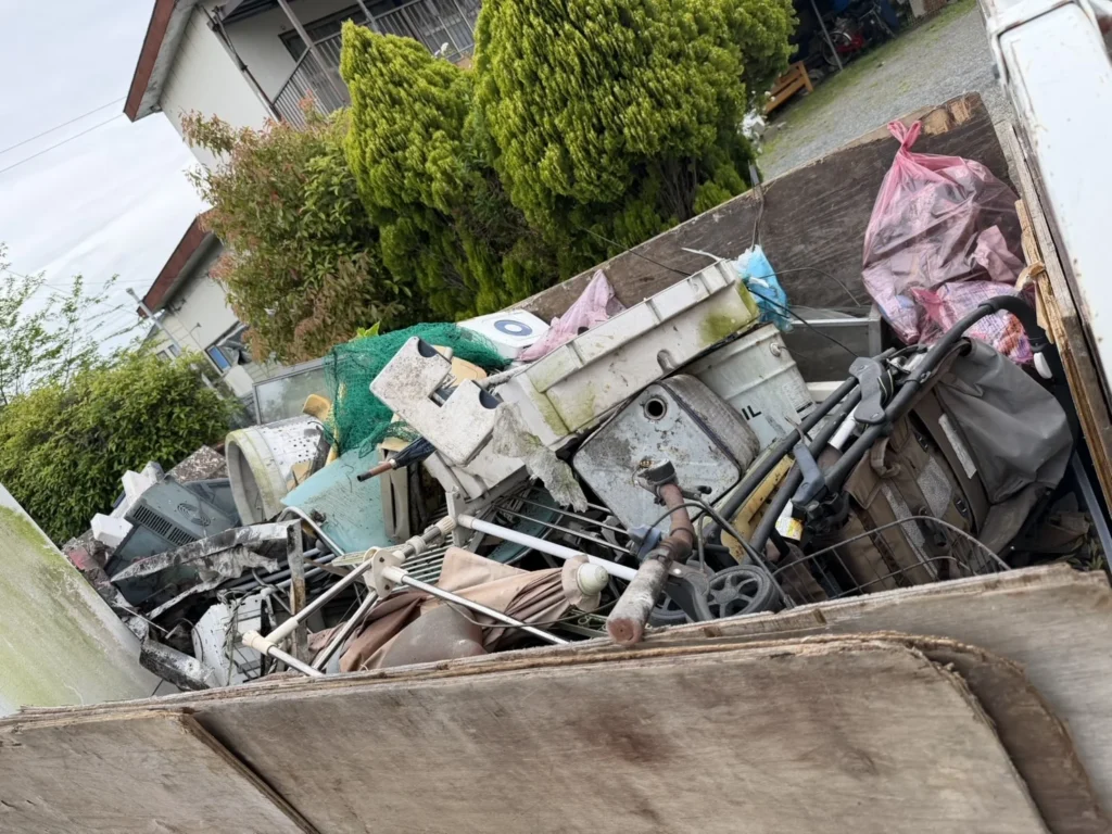 福岡市東区香椎の庭・物置の片付けで、洗濯機の部品やベビーカー、金属製の枠などを積んだ作業途中のトラック荷台