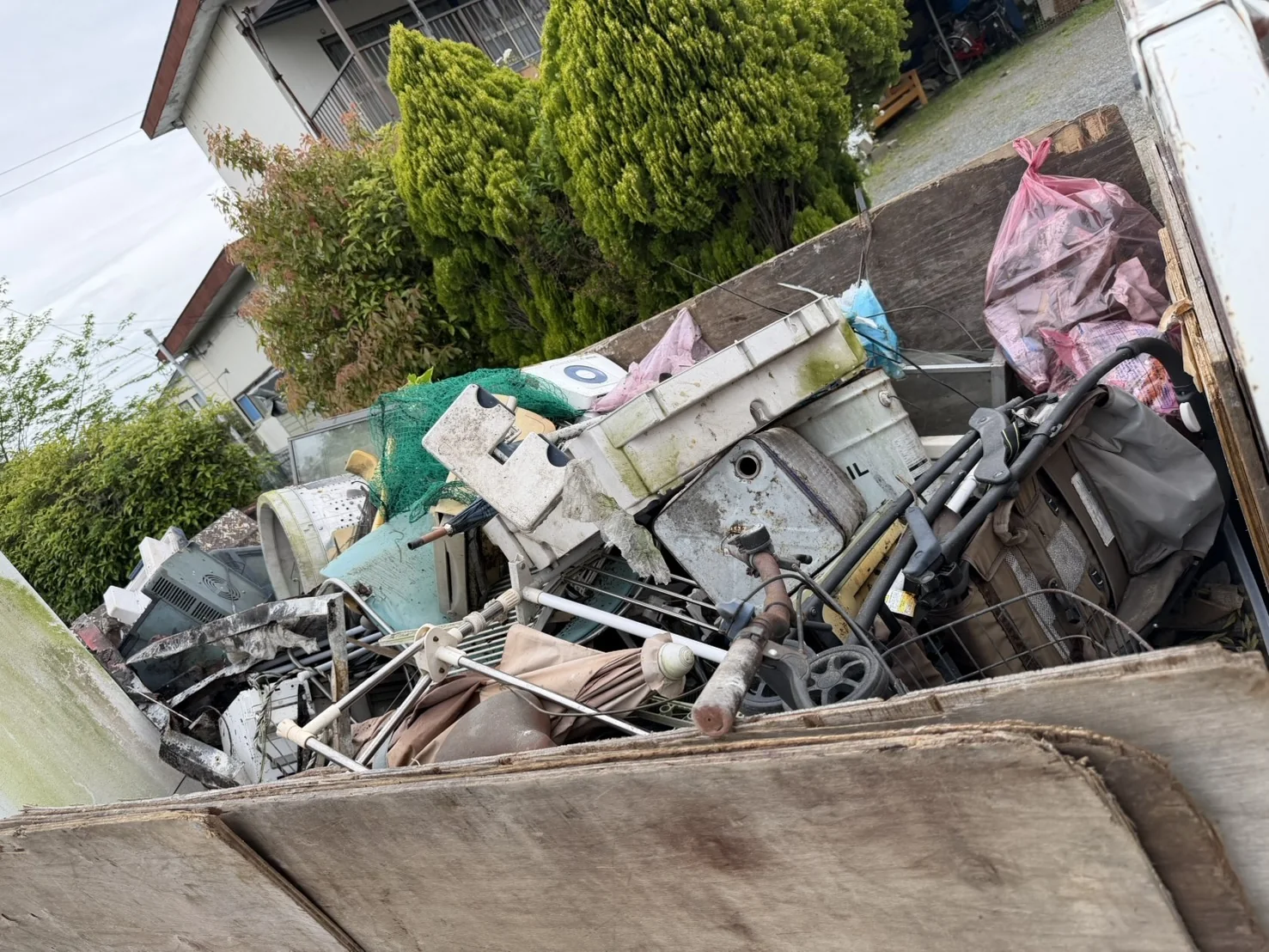 福岡市東区香椎の庭・物置の片付けで、洗濯機の部品やベビーカー、金属製の枠などを積んだ作業途中のトラック荷台